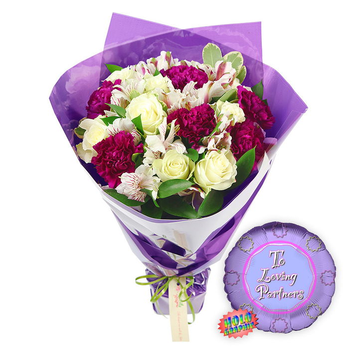 This image showcases a celebratory bouquet with a matching balloon, perfect for a graduate, set against a plain white background that highlights every detail. The bouquet is upright and slightly fan-shaped, wrapped in a smooth, rich purple paper that forms clean, angular folds around the stems. The paper narrows towards the base, where it is secured with a decorative green and white ribbon that adds both colour contrast and a sense of occasion, much like a ceremonial ribbon you might see at a prize-giving near Mill Hill School. From this base springs a harmonious selection of fresh flowers. Several creamy white roses, their petals tightly layered in spiralling whorls, create focal points of calm and classic beauty, evoking a sense of achievement and dignity. Interspersed among them are voluminous clusters of deep fuchsia or magenta blooms, probably carnations or chrysanthemums, whose ruffled petals and rounded forms contribute an exuberant, almost jubilant feel. Fine white filler flowers, reminiscent of baby's breath, weave delicately between the larger blossoms, dotting the arrangement with small, cloudlike tufts that soften the strong colours. Around the flowers, glossy green leaves in simple, elegant shapes add volume and structure, framing the bouquet with a natural freshness that could easily have been gathered from gardens around Mill Hill and its leafy streets. Just to the lower right, a round purple Mylar balloon sits on the white surface, its metallic finish reflecting subtle highlights. In graceful white script across the centre, the words To a Loving Graduate express gratitude and pride, making the theme immediately clear. Beside the balloon, a small oval label or sticker, marked with touches of green and white, suggests branding or quality assurance from a professional florist. The entire composition feels both joyful and thoughtful, an ideal choice for marking exams, graduations, or academic milestones for students and families in the Mill Hill area.