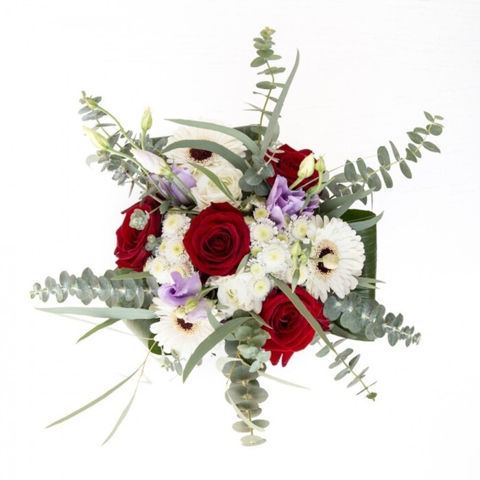 From the experienced hands of a Mill Hill florist, this bouquet is a testament to quiet confidence and seamless harmony. Radiant white gerberas with bold, espresso-hued centres anchor the design, while plush, deep red roses spiral gracefully at the heart, embodying intense emotion. Lavender lisianthus, offering a delicate contrast in both bud and bloom, evoke the wild charm of Mill Hill's local nature reserves. Wisps of eucalyptus weave through the bouquet, bringing a silvery-green luminosity and a breath of invigorating fragrance. Accenting the ensemble, clusters of fluffy white filler flowers introduce soft, tactile layers, their arrangement reminiscent of low-lying morning mist over Mill Hill Park. A collar of robust, verdant leaves encircles the base, creating a refreshingly clean finish, all presented within a transparent vase where fresh stems and sparkling water invite admiration. Designed for meaningful celebrations or to brighten a neighbour's day, this arrangement reflects the thoughtful creativity and natural elegance of Mill Hill's blossoming community.