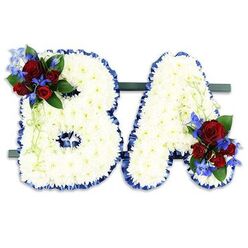 A composed and reverent floral tribute spelling the uppercase initials B and A, each letter expertly formed from a dense sea of small white chrysanthemums. The many tiny petals are layered to create a soft, textured surface that mutes shadows and catches a gentle, natural light, conveying calm and purity. Along the outer edge of both letters, a rich royal-blue satin ribbon is carefully wrapped and ruffled, its sheen providing crisp definition and a dignified contrast to the white chrysanthemum field.

Accenting the design are two matched clusters: the B's upper left curve holds a concentrated spray of deep red roses - from tight buds to partly opened cups - intermingled with vivid blue, delphinium-like spikes; the A's lower right bears a mirrored grouping. Lush dark green foliage and slender pale-green tendrils lace through these accents, adding depth, movement and a subtle scent that lifts slightly against the clean white blooms. The initials sit side-by-side on a narrow dark-green base designed for stable placement in a church entrance or beside a graveside service.

Prepared with the attentive care families expect from a neighbourhood florist, this style of bespoke letter tribute is often chosen to personalise a memorial. At Flowers Mill Hill we source blooms for lasting form, mindful of local services around Mill Hill Broadway and Mill Hill Village. The overall effect is one of measured dignity and warming memory - white for peace, blue for strength, red for love - presented with quiet craftsmanship and a local understanding of what brings consolation.