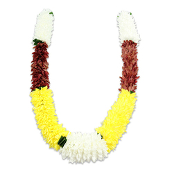 This U-shaped traditional mala is presented on a stark white background, photographed with a soft shadow that highlights its substantial volume and fine craftsmanship. Each symmetrical arm begins with a compact, cylindrical band of soft, creamy-white blooms-reminiscent of small chrysanthemums or jasmine-giving a light, fluffy top to the garland. Below the white, a short, dense segment of deep maroon or reddish-brown petals introduces a rich, grounding chord before yielding to the longest portion: a lavish expanse of bright yellow fabric flowers that curve to form the lower sweep. At the curve's centre, where both yellow arms join, a wide, plush cluster of pure white chrysanthemum-like flowers creates a luminous focal point, subtly accented by tiny dark-green leaf motifs that separate the colour blocks and add a touch of natural contrast. The construction is meticulous: countless synthetic petals layered and arranged to evoke the feel of fresh flowers while offering durability for repeated ceremonial use. Visually and emotionally, the garland reads as both celebratory and reverent-perfect for Hindu puja, temple offerings, weddings, and festivals such as Diwali or Holi. Prepared with the attention of a neighbourhood artisan, this piece is the kind of traditional adornment Flowers Mill Hill would recommend for Mill Hill Broadway events, community gatherings at Mill Hill Park, or as an elegant home offering; it balances cultural symbolism-purity, prosperity, devotion-with practical longevity, and the colours sing against the neutral background in a way that feels intimate and respectful.