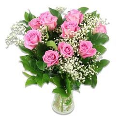 In this image, a cluster of pink roses and baby's breath rises from a straight-sided clear glass vase, set against a perfectly white background that draws full attention to the flowers, much like an arrangement displayed in the window of a Mill Hill florist on a bright morning. About ten to twelve roses form the focal point, their stems trimmed to a uniform length so that the blooms gather into a smooth, rounded silhouette. The rose petals show a gentle interplay of soft and medium pinks; the outer petals curl slightly back, paler and almost translucent at the edges, while the deeper central petals wrap around each other in tighter spirals of more saturated colour. Nestled between the roses, clusters of white baby's breath (Gypsophila) appear like tiny constellations, each airy stem holding many delicate blossoms that introduce a sense of lightness and innocence, making the arrangement particularly appropriate for baby celebrations or christening flowers. The roses and baby's breath are framed by an understated collar of dark green foliage, the leaves glossy and clean, reflecting just enough light to create subtle highlights that add depth to the composition. Through the sides of the vase, the viewer can see the neat bundle of stems immersed in clear water, confirming that this is a fresh, carefully prepared bouquet, ready for delivery to homes around Mill Hill Broadway or along Flower Lane. The lighting is even and flattering, emphasising the velvety quality of the rose petals and the airy fineness of the baby's breath without creating harsh contrast. The arrangement projects a feeling of tender joy and understated luxury, the kind of bouquet families in Mill Hill might choose to welcome a new baby or express heartfelt congratulations with gentle, classic style.