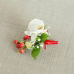 A detailed, close-up top-down photograph shows a handcrafted floral boutonniere resting on a softly textured, oatmeal-coloured linen fabric, the kind you might see on wedding tables in Mill Hill's country-style venues. At the heart of the design is a pristine white Phalaenopsis orchid bloom, its broad petals gently unfurling like porcelain wings. The orchid's centre glows with a subtle wash of creamy yellow and soft orange, giving warmth and depth to the otherwise cool white. Surrounding this focal flower are airy clusters of tiny white baby's breath, their cloud-like blossoms softening the edges and adding a romantic, misty texture. Nestled just to one side, a tight cluster of glossy, round red berries provides a lively pop of colour, reminiscent of winter walks around Mill Hill Park, while a few paler green, oval buds hint at new growth and freshness. Slender and broader green leaves, polished and vibrant, weave through the flowers and berries, framing the orchid and balancing the composition. The stems are neatly bound at the base with a vivid red satin ribbon, wrapped with precise, even folds and tied into a small, compact knot, with short tails that lie smoothly against the fabric. The natural beige background keeps the focus squarely on the interplay of white petals, red berries, and lush greenery, creating an impression of quiet elegance. The whole boutonniere feels ready to be pinned to a groom's lapel for a Mill Hill wedding, worn for prom photographs on The Ridgeway, or chosen for any formal celebration where a small, exquisite floral detail close to the heart speaks of care, joy, and timeless style.