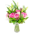 A vibrant, eye-catching bouquet of deep pink roses and ivory-white lilies sits in a clear glass vase, photographed on a clean white backdrop so every texture and hue is easy to imagine. Several large roses take the visual lead-their velvety petals unfurl in layered shades of fuchsia and blush, each curl catching a soft, even light that suggests a cool, early-morning freshness. White lily buds thread through the pinks: some tightly furled with green-tinted tips, others just parting at the edge to show glimpses of trumpet-shaped white petals and pale stamens. The arrangement is full-bodied and rounded, built around abundant green foliage that ranges from broad glossy leaves to finer, feathery sprigs; this verdant volume cradles the blooms and makes the pinks and whites read as luminous against the neutral background. Small, darker burgundy or reddish-brown accent buds are woven in, lending a subtle depth and gentle contrast that keeps the eye moving across the composition.

The vase is simple and transparent, with a slightly tapered base; clear water reveals neatly trimmed green stems and the natural geometry of the bouquet beneath the surface. As a florist describing this piece, I notice the balance between the boldness of the roses and the poised restraint of the lily buds-a combination that feels celebratory and tender at once. The scent is implied: a soft, powdery sweetness from the roses with the faint, clean perfume of lilies. This arrangement would work beautifully as a birthday surprise, a thoughtful anniversary gift, or a bright, calming centrepiece for a living room in Mill Hill, where fresh-cut flowers lift the mood and invite a quiet sense of wellbeing.