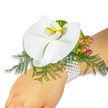 A single, elegant wrist corsage rests gently on a fair-skinned wrist against a pristine white backdrop, photographed in soft, even light so every texture reads clearly. At the center sits a large white Phalaenopsis orchid - the moth-like bloom opening with broad, satiny petals that curve with a quiet, architectural grace. The orchid's labellum shows a concentrated wash of bright yellow warming into a touch of orange at its throat, a tiny sunlit focal point amid the pure white petals. Underpinning the bloom, airy sprays of asparagus fern fan out in a feather-like halo, their vivid green providing both depth and a delicate, lacey contrast to the orchid's smooth surface. To one side, a small cluster of round Hypericum berries tucks into the foliage; their skins graduate from pale chartreuse through rose to a warm cranberry, suggesting both seasonal richness and careful selection. A whisper of ruffled lime-green accent foliage adds another textural note, catching the light with a gentle sheen. The corsage is secured on a multi-strand bracelet of small white pearls that sit cool and luminous against the skin, lending a timeless, heirloom quality to the piece. The overall effect is romantic and composed - a floral accessory suited to weddings, proms, or quiet celebrations - that reads as both contemporary and classic. As a local Mill Hill florist would note, the restrained palette of white, green, and berry-red reads beautifully in photographs and real life alike, offering a subtle, sophisticated statement for anyone attending a formal event in Mill Hill Village or nearby Mill Hill Park.
