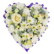 A graceful heart-shaped sympathy tribute is set against a bright white background, its restrained palette and lush texture creating a moving, contemplative effect. The surface of the heart is entirely covered with fresh white and cream flowers, giving the arrangement a plush, cushion-like appearance that looks soft and gentle. At the very centre, a single creamy white rose unfurls in perfect spirals, inviting the eye to pause and reflect on the life being honoured. Around it, white carnations provide the main body of the design, their characteristic ruffled petals overlapping to form a billowy, comforting layer. Nestled amongst the carnations are white spider chrysanthemums and daisy-type blooms, their long, fine petals radiating from small centres tinted with pale green or soft yellow, bringing subtle light and variation to the composition. Smaller cream roses and delicate buds, possibly lisianthus or miniature carnations, are carefully dotted throughout, lending detail and the impression of many individual memories woven together. Blue-green eucalyptus foliage, with its rounded, slightly silvery leaves, is tucked here and there between the flowers, introducing a cool, natural contrast reminiscent of the mature trees and open skies that define parts of Mill Hill. Framing the heart is a deep lavender to rich purple ruffled ribbon, pleated into gentle scallops that trace the contours of the design and add a solemn, respectful finish. The overall effect is of a thoughtfully crafted memorial piece, much like those prepared by experienced Mill Hill florists for funerals, cremations, or memorial gatherings, offering a visual language of peace, sympathy, and enduring love for families across the local community.