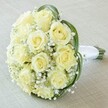 This close-up, high-angled image highlights a classically styled bouquet, designed with care by local Mill Hill florists for a milestone occasion. Dominating the view are about a dozen creamy white to pale yellow roses, each bloom pristine, petals soft and elegantly unfurling. Interspersed among the roses, airy puffs of baby's breath (gypsophila) lend an ethereal, cloud-like lightness and accentuate the arrangement's romantic mood. Elegant arcs of deep green leaves sweep gracefully around the perimeter of the bouquet, their vivid hues bringing energetic contrast to the delicate flowers. To one side, the bouquet's stems are gracefully banded with radiant white satin ribbon, attesting to the skill and attention to detail familiar in Mill Hill floral design. All of this rests on a subtly textured, neutral fabric backdrop, allowing the intricate textures and colours to stand out-ideal for a wedding, anniversary, or refined celebration anywhere from Mill Hill Village to Mill Hill Broadway. This bouquet radiates purity, elegance, and local pride, making it a perfect expression of love or joyous occasions within the community.