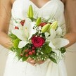 With the verdant tranquility of Mill Hill as its muse, this bridal bouquet pulses with heartfelt intention and timeless grace. Large, open white lilies form the centerpiece, their petals like silk ribbons cascading softly beside the bride's textured white gown, capturing light that pours through country church windows. Nestled within, crimson roses add a rich, romantic glow-every spiral suggesting enduring love and new beginnings. Bright red berries and moss-green orbs peek playfully throughout the bouquet, infusing it with joyful energy, while airy clouds of baby's breath scatter whispers of blessing. Threads of feathery green foliage and the sheen of broader leaves lend texture and fullness, reminiscent of handpicked blooms from the fields and gardens near Mill Hill Broadway. The bride's fingers, gently wrapped around the stems, ground the moment in real intimacy and hope. Created with care by a skilled local florist, this design combines beauty, freshness, and the distinct charm of Mill Hill-making it a perfect statement for a wedding day filled with anticipation and memory.