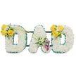 A tender, three-dimensional memorial piece spelling 'DAD' in large, freestanding capital letters, each letter crafted from a dense blanket of pristine white spray chrysanthemums (or similar small white florets) so the surface reads soft, pillowy and uniform. The rounded block forms sit against a clean white backdrop and are crisply edged with a ruffled, deep emerald-green satin ribbon that catches the light and gives each letter a clear silhouette. Slim dark-green metal support bars run horizontally behind the letters, visible at the rear, anchoring them as a single cohesive tribute. On the leftmost 'D' a bright cluster of sunlit yellow roses - three or four open blooms - is set on the upper curve, paired with delicate white filler flowers like freesias or gypsophila and fresh glossy foliage; two long, bare green stems arch diagonally across toward the centre, creating movement. The central 'A' carries a quieter, elegant grouping on its lower diagonal, featuring two deep purple to burgundy calla lilies with their smooth, trumpet-shaped forms surrounded by small white accents and leafy greens, offering a solemn focal point. The rightmost 'D' mirrors the left, with an identical spray of yellow roses and white filler on its upper curve. The overall impression is one of respectful craftsmanship: clean, composed, and soothing. Subtle scent of fresh chrysanthemums and roses would be gentle rather than overpowering. This arrangement reads as a dignified funeral tribute for a father or father figure - a visual language of purity, remembrance and warmth, suitable for memorial services in and around Mill Hill and local chapels or family homes.