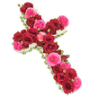 In this photograph, a meticulously arranged floral cross is displayed on a bright white background, its form rich with colour and texture. The entire surface of the cross is layered with roses, with deep red blooms taking centre stage. These red roses are fully open, their velvety petals forming dense, overlapping spirals that create a continuous band of crimson along both arms and the central stem. Their intense, almost wine-like shades convey deep affection, respect, and the solemn weight of farewell. Interlaced with them are vivid fuchsia pink garden roses and similarly full-petalled flowers, slightly lighter in tone and more ruffled in form, bringing a gentle warmth and tenderness to the composition. Smaller buds in coordinating reds and pinks are scattered throughout, adding visual interest and symbolising memories that are still blooming in the hearts of those left behind. Around the outer edge, a neat line of tiny white blossoms - most likely spray chrysanthemums, small carnations, or gypsophila - traces the cross's silhouette, lending it a soft, cloud-like border that suggests purity, peace, and hopefulness. Delicate touches of fresh green foliage or slender leafy strands peek subtly from beneath the flowers, giving a whisper of natural structure. The image is lit with soft, even light, making each colour and petal detail stand out without harshness, creating an atmosphere of calm reflection. This style of floral cross would sit beautifully in a Mill Hill chapel or at a memorial near local green spaces, a thoughtful tribute that balances strong faith with gentle remembrance.
