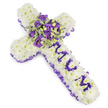 A quietly reverent floral cross designed to read at a glance as both a symbol of faith and a personal farewell. The body of the cross is densely carpeted with pristine white chrysanthemum heads, each petal layered to form a soft, pillowy surface that seems almost to sigh with calm. Along the entire outer edge a ruched purple satin ribbon frames the shape, its ruffled texture creating a gentle shadow that accentuates the cross's silhouette against the plain white background. Down the vertical shaft, the name MUM is lovingly spelled in rich purple flower heads - compact eustoma or small spray chrysanthemums - the letters raised just enough to be tactile and clearly legible from a short distance. At the intersection of the arms a lush central spray becomes the arrangement's heart: deep violet and lighter lavender roses mingle with ruffled lilac lisianthus, interspersed with variegated green foliage whose pale margins and darker centres give the cluster depth and a whisper of spring. Tiny green berries peek through, adding a crisp, rounded contrast to the velvety petals. The cool palette of white and layered purples, set in soft, diffuse light, evokes dignity and quiet consolation; there is a faint, powdery scent of blossoms, like a calm garden path after rain. As a local Mill Hill design, this tribute suits a funeral service at Mill Hill Cemetery or a memorial gathering near Mill Hill Broadway - a composed, tactile expression of respect and enduring affection for a beloved mother.