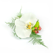 A single, pristine white Phalaenopsis orchid is captured at the center of this compact corsage, its broad, satiny petals unfolding like a small, luminous fan against a clean white backdrop. The orchid's throat shows a soft wash of yellow and warm gold with faint brown veining, lending a subtle warmth to the otherwise cool white bloom. Surrounding the blossom, feathery sprigs of asparagus fern arch outward to the left and cascade gently to the right, their fine, airy texture contrasting with the orchid's smooth, waxy surface. On the right, clusters of small reddish-pink hypericum berries add a cheerful, organic pop of color, while a tight cluster of lime-green chrysanthemum or similar filler brings a zesty, almost succulent brightness beneath the bloom. The whole composition reads as deliberately asymmetrical yet balanced, with negative space that keeps the design feeling light and wearable. Soft studio lighting highlights the petals' sheen and the fern's delicate filaments, creating subtle shadows that emphasize depth and tactility. Imagined as a lapel pin or wrist corsage, the arrangement conveys refined simplicity-appropriate for a wedding, prom, or formal evening-where the wearer wants an accessory that feels both contemporary and timeless. The scent is a quiet, green freshness from the foliage rather than an overpowering perfume, and the piece's scale and construction suggest it would sit comfortably pinned to a jacket or tied to a ribboned wristband. As a local Mill Hill florist might note, the design's clean lines and fresh palette reflect the quiet elegance often requested for neighbourhood ceremonies and intimate celebrations held around Mill Hill Park and the Broadway.