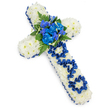 A traditional Christian cross composed entirely of fresh flowers is pictured laid flat on a bright white surface, the image capturing both its structure and emotional weight. The cross is densely covered with white spray chrysanthemums, their small, round blooms packed closely together so that no gaps show between them. This dense layering of petals creates a thick, plush texture that appears both soft and substantial, like a carefully prepared cushion of flowers laid in tribute. The white blooms are cool and calm in tone, offering a sense of serenity reminiscent of a quiet service in a Mill Hill chapel or crematorium. Encircling the full outline of the cross is a royal blue satin ribbon, gently pleated and anchored along the edges. The ribbon's deep colour stands in striking contrast to the white petals, framing the piece like a refined border and giving it a polished, commemorative feel.   

At the intersection of the cross's arms, a prominent cluster of royal blue flowers forms the central feature. Ruffled blue carnations, their petals layered and gently curled, sit alongside more slender blue flowers that mirror the shape of delphiniums or orchids, rising slightly above the surrounding chrysanthemums. Dark green ferns and leafy foliage cradle this central spray, providing texture and a natural, garden-like touch. Running down the vertical arm of the cross, the word DAD has been fashioned from the same royal blue satin ribbon that frames the tribute. Each letter has been individually looped and arranged so it clearly stands out against the white background, making this cross a deeply personal memorial for a father. The overall arrangement feels composed, respectful, and tender, well suited for funeral services or graveside farewells in Mill Hill where families wish to express profound love and remembrance.